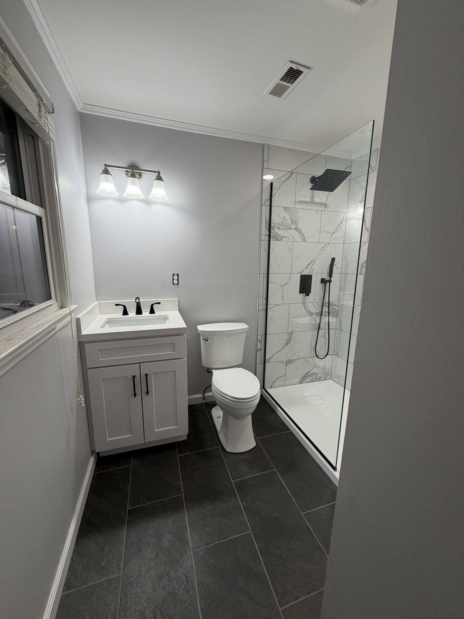 Bathroom with a white vanity, walk-in shower and dark plank-look tile floor