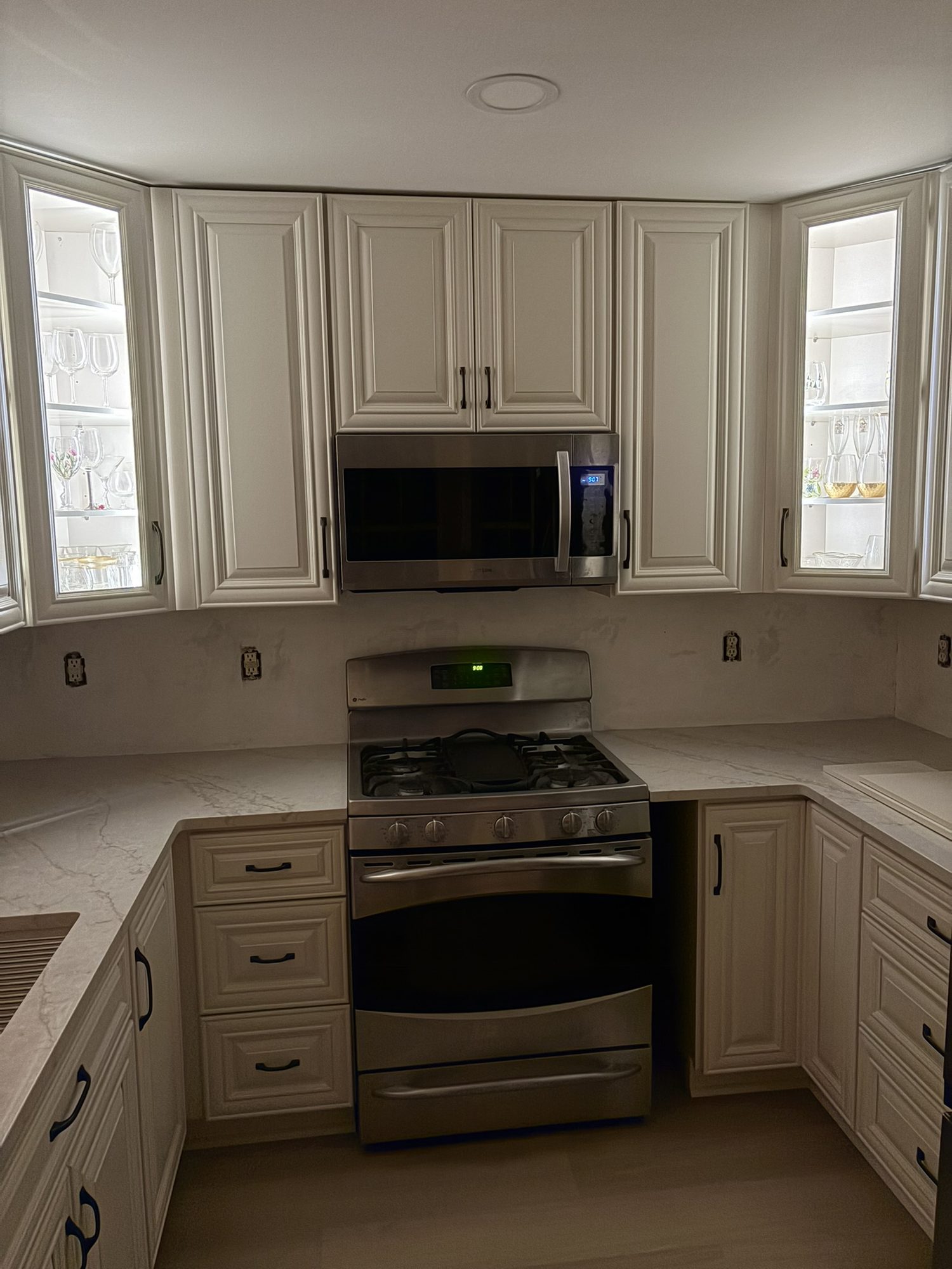 Cream raised-panel kitchen cabinets with lighted glass-front corner cabinets