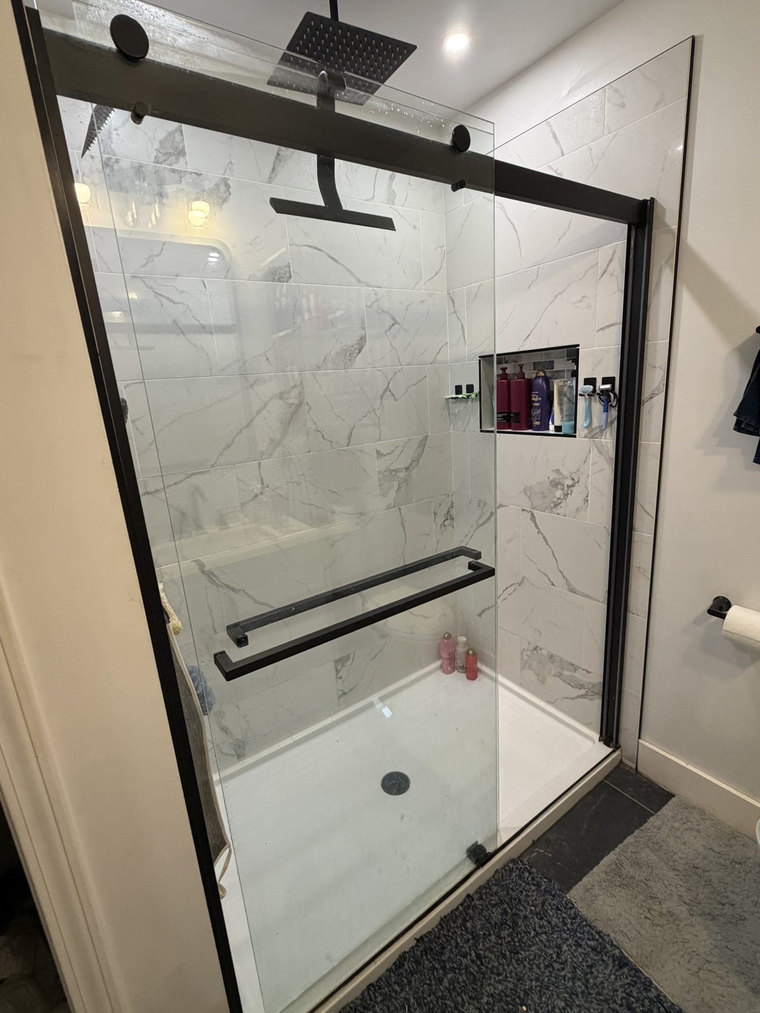 Tile shower with a black-framed sliding glass door