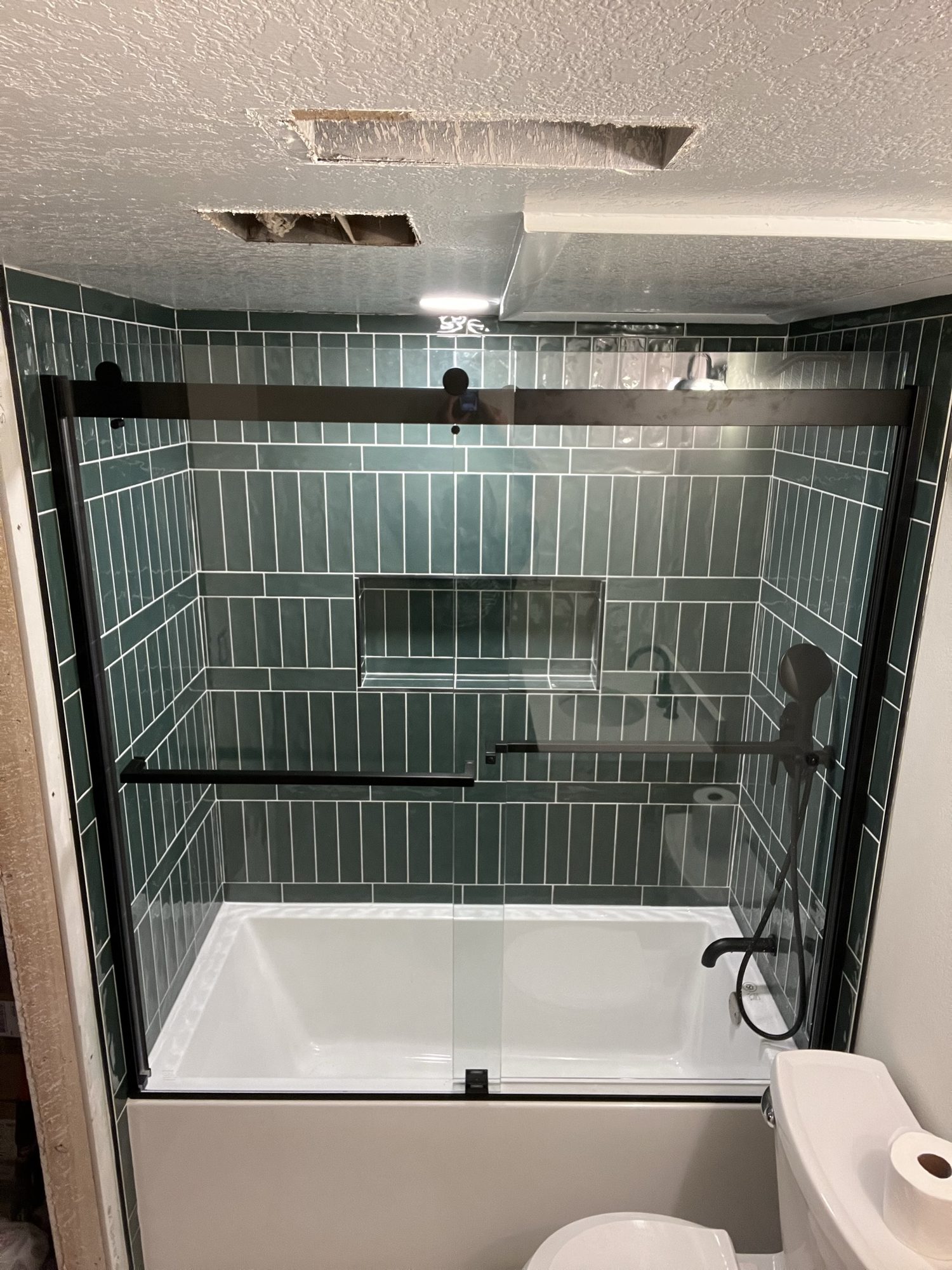 Green subway-tile tub surround with a glass door